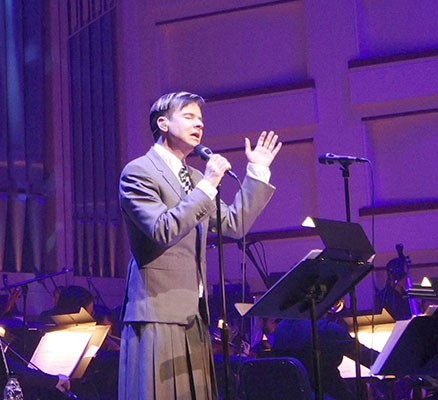 Photo of John Cameron Mitchell singing with orchestra on stage