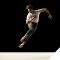 Photo of a male dancer in mid-air above an empty stage